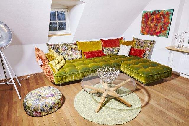 Sofa mit Recamiere mit grünem Samtpolster und bunten Kissen