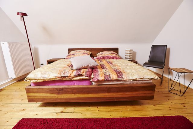 Doppelbett aus dunklem Holz mit Bettwäsche
